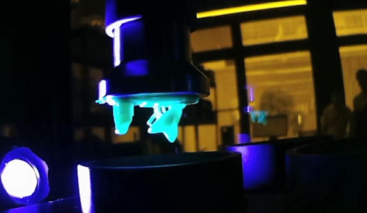 A printed part under UV post-curing light on the lab bench.